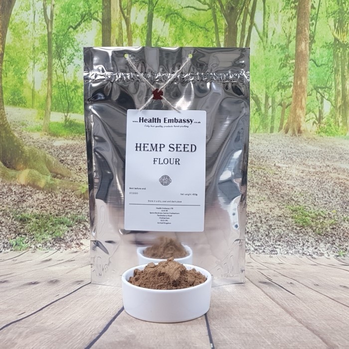 Health Embassy Hemp Seeds Flour in white porcelain bowl next to pouch on wooden table