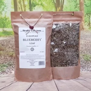 Dried and cut European Blueberry Leaf in an eco paper bag on wooden surface with green background