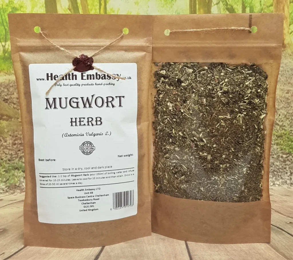 A styled product shot featuring a kraft bag of Health Embassy Mugwort Herb with dried leaves spilling onto a rustic surface.